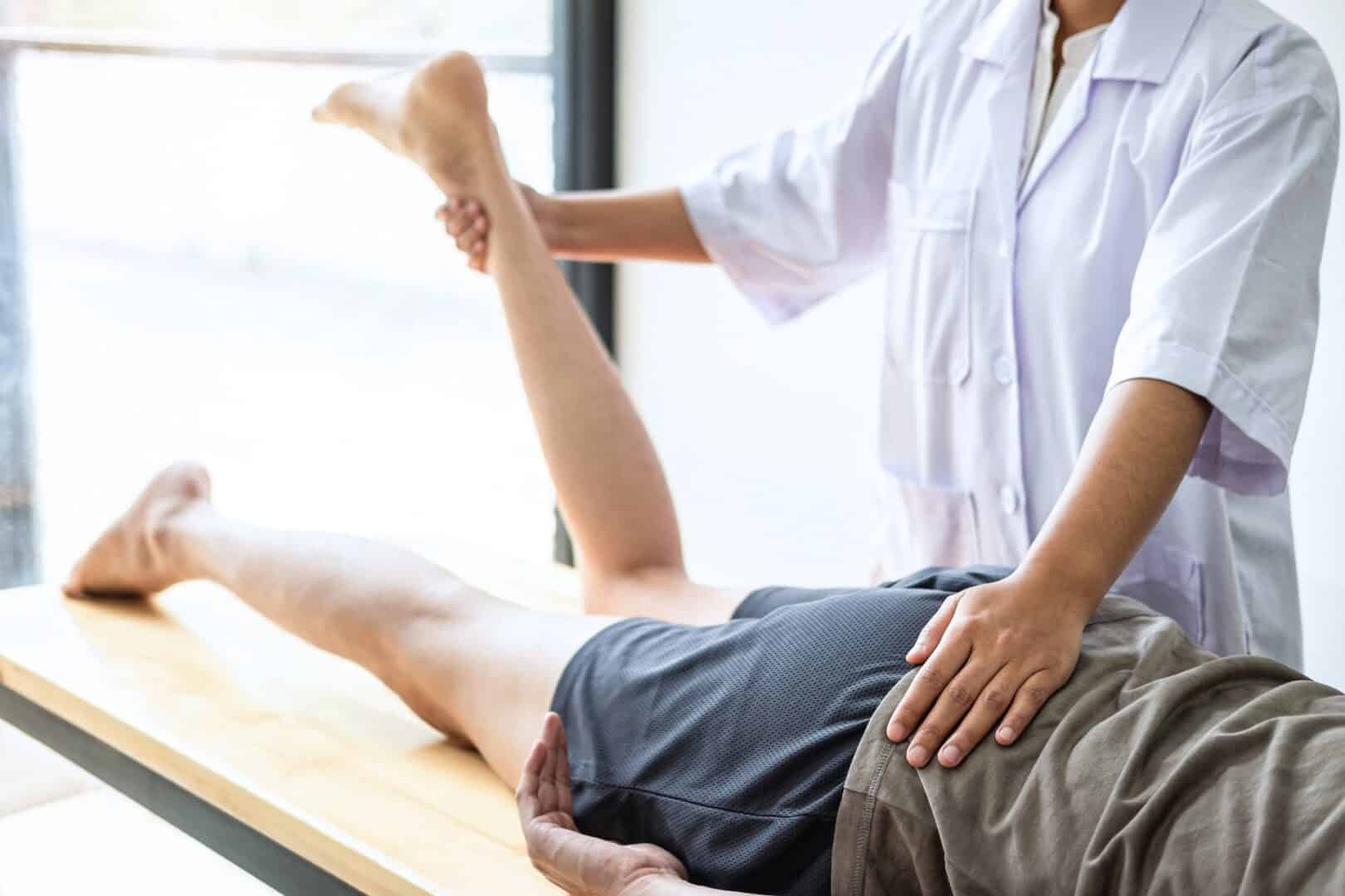 doctor or physiotherapist working examining treating injured leg